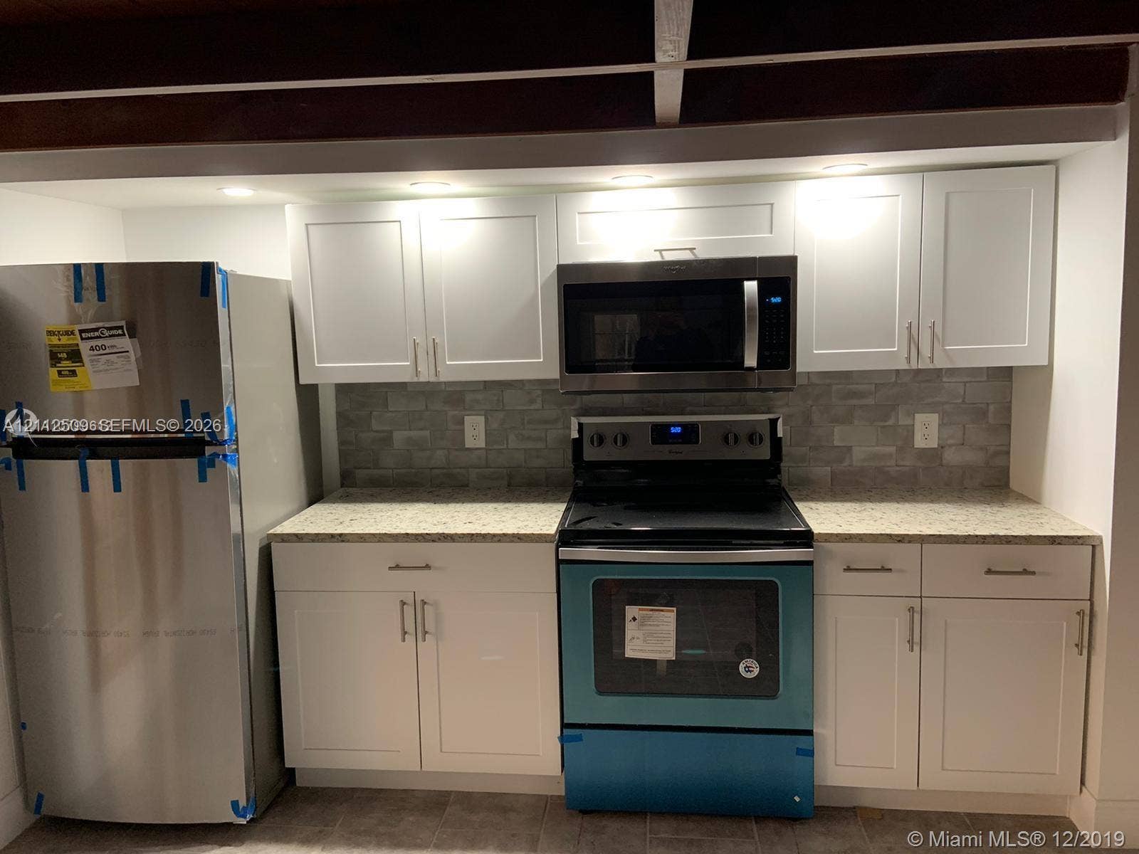 215 4th Street, #1, Jupiter, Jupiter, FL 33458 Kitchen featuring white shaker-style cabinetry, stone-finish countertops, stainless steel appliances, and a gray tile backsplash