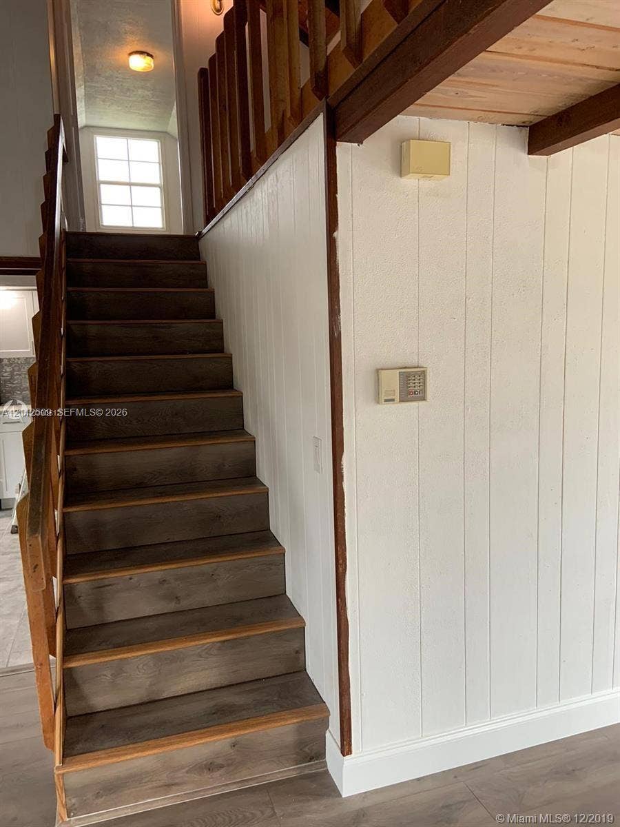 215 4th Street, #1, Jupiter, Jupiter, FL 33458 Staircase with wood-finish treads, vertical paneling, and a natural wood-finish railing