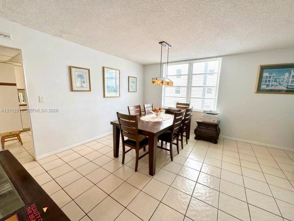 9250 W Bay Harbor Drive, #4A, Bay Harbor Islands, FL 33154 Spacious area featuring light-toned ceramic tile flooring, horizontal window blinds, and a multi-light metal pendant fixture