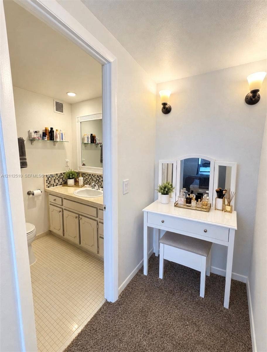 9250 W Bay Harbor Drive, #4A, Bay Harbor Islands, FL 33154 Bathroom featuring a vanity with a countertop basin, mosaic tile backsplash, framed wall mirror, and two wall-mounted light fixtures