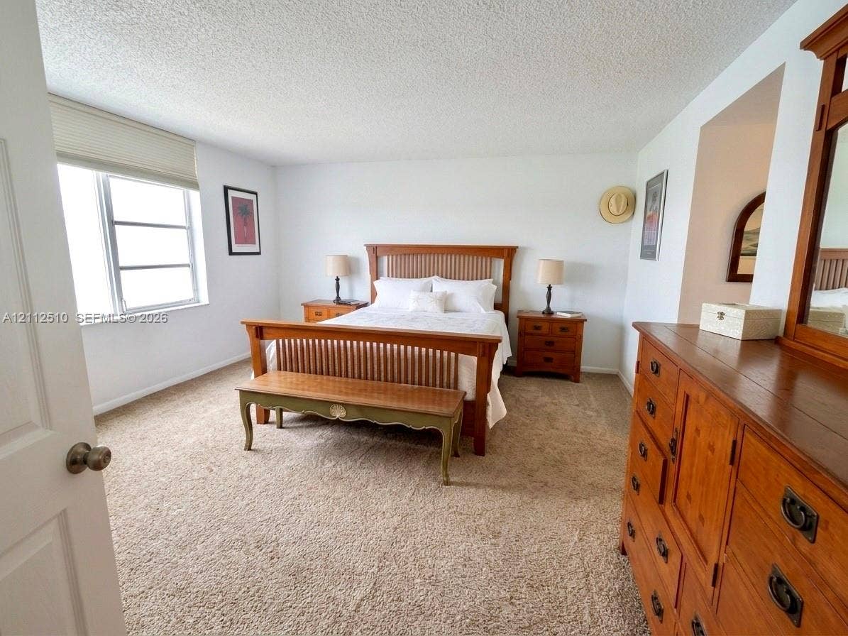 9250 W Bay Harbor Drive, #4A, Bay Harbor Islands, FL 33154 Neutral-toned carpeting, multi-pane window with custom shade, and textured ceiling