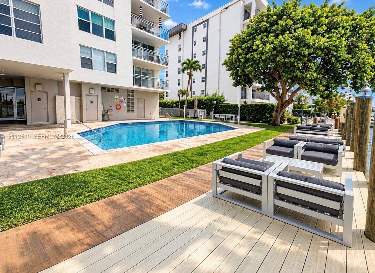 9250 W Bay Harbor Drive, #4A, Bay Harbor Islands, FL 33154 Swimming pool with a stone pool deck, wood-finish decking, and manicured lawn