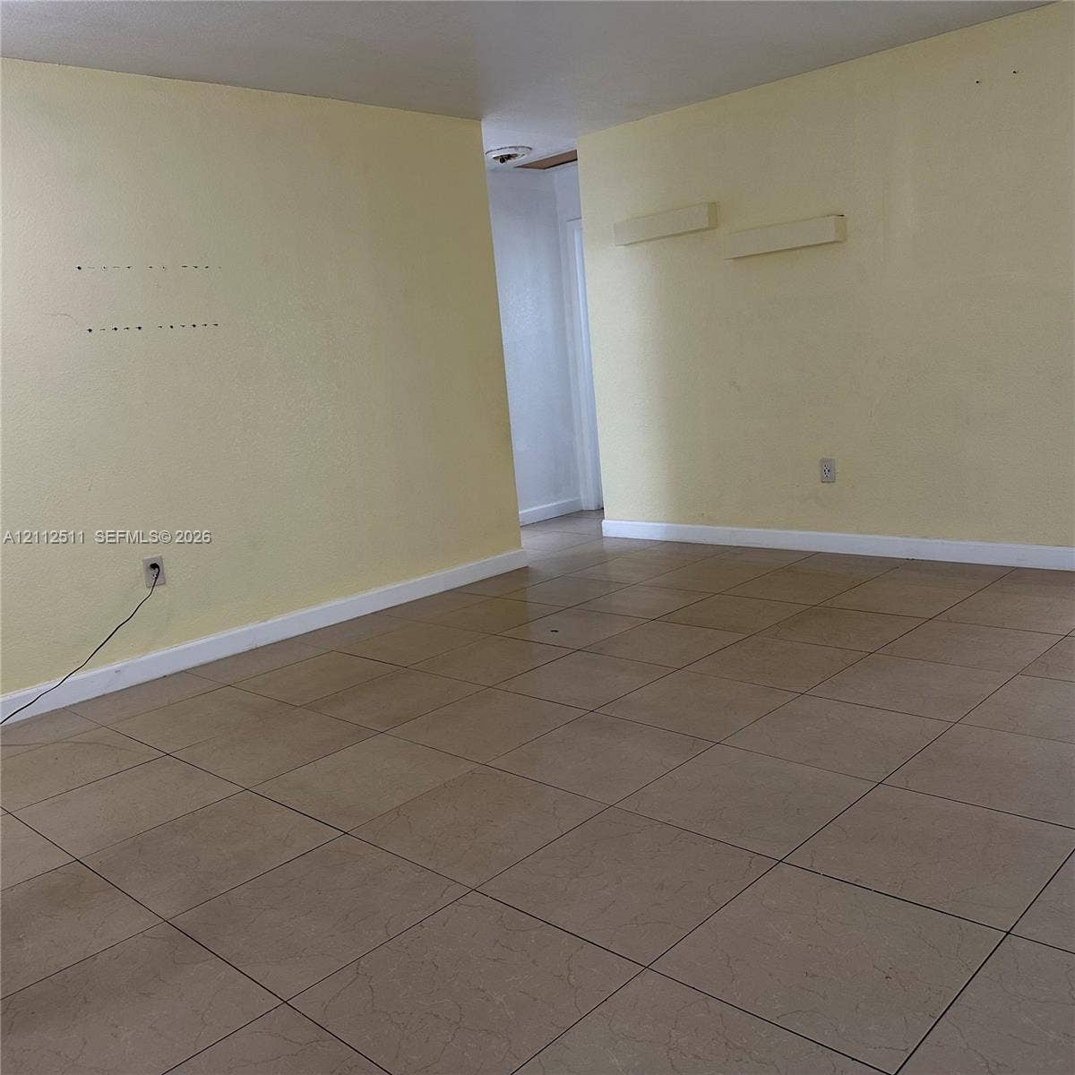Interior space featuring large-format ceramic floor tiles and painted walls with wall-mounted lighting fixtures