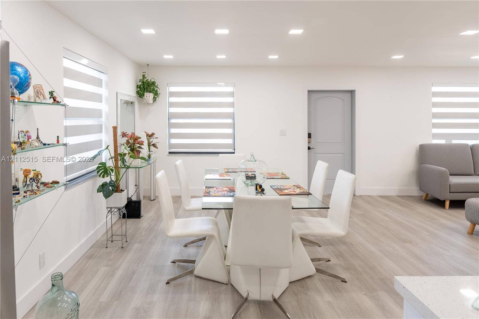 Hallandale Beach, FL 33009 Neutral-toned wood-finish flooring, recessed lighting, banded roller shades, and integrated glass shelving