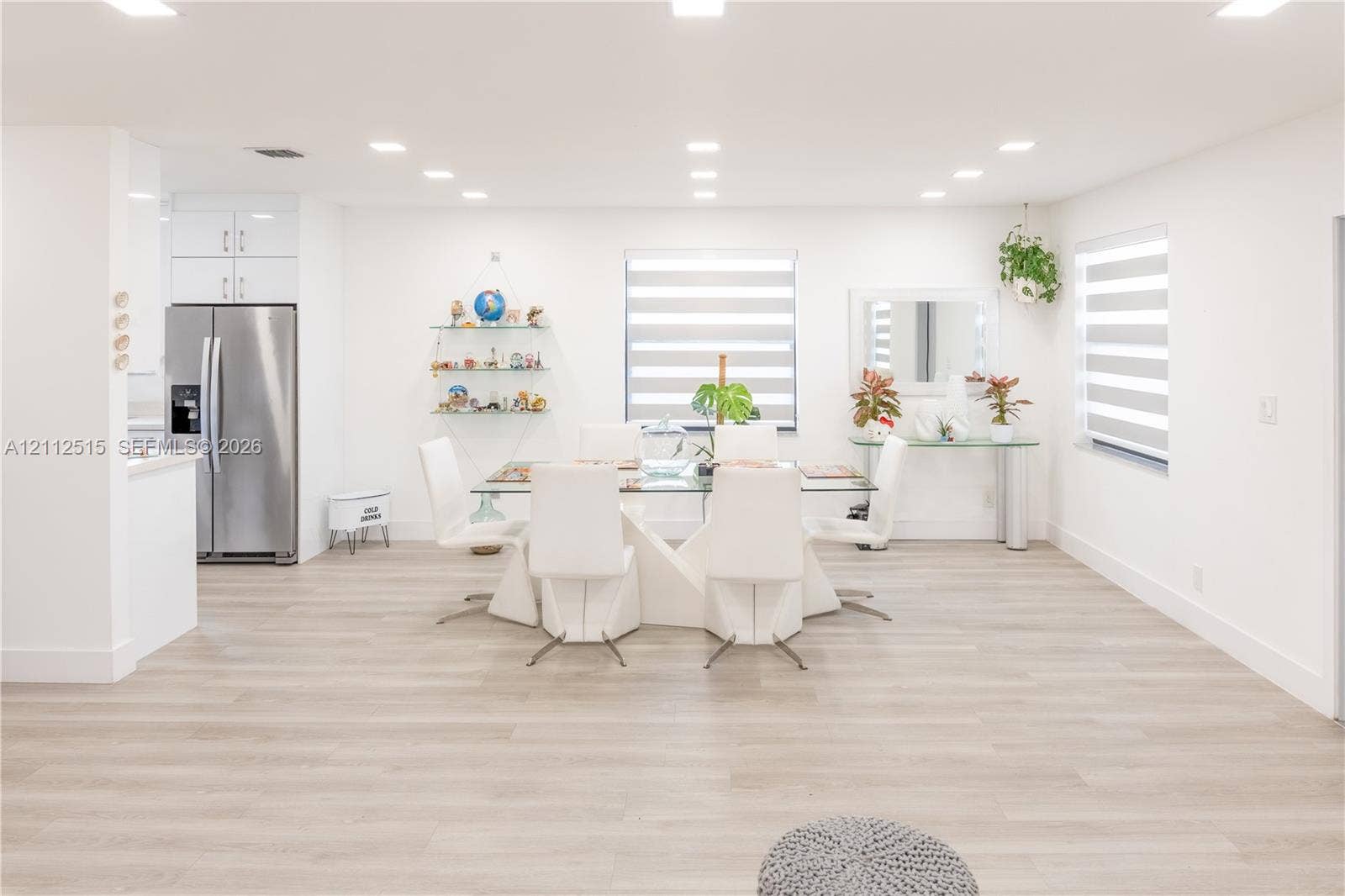 Hallandale Beach, FL 33009 Open-concept interior featuring light wood-finish flooring, recessed lighting, white gloss cabinetry, and dual-layered window treatments