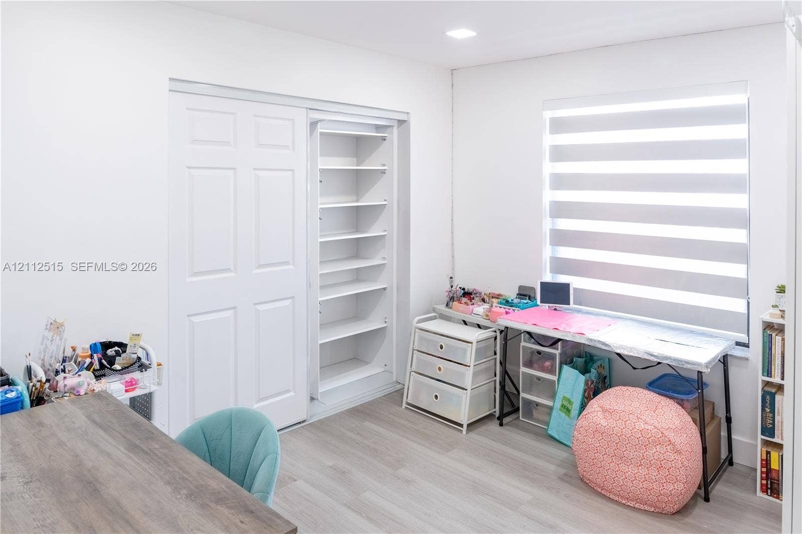 Hallandale Beach, FL 33009 Room featuring light-toned wood-finish flooring, recessed ceiling lighting, a built-in closet with multi-tier shelving, and dual-layered cellular shades