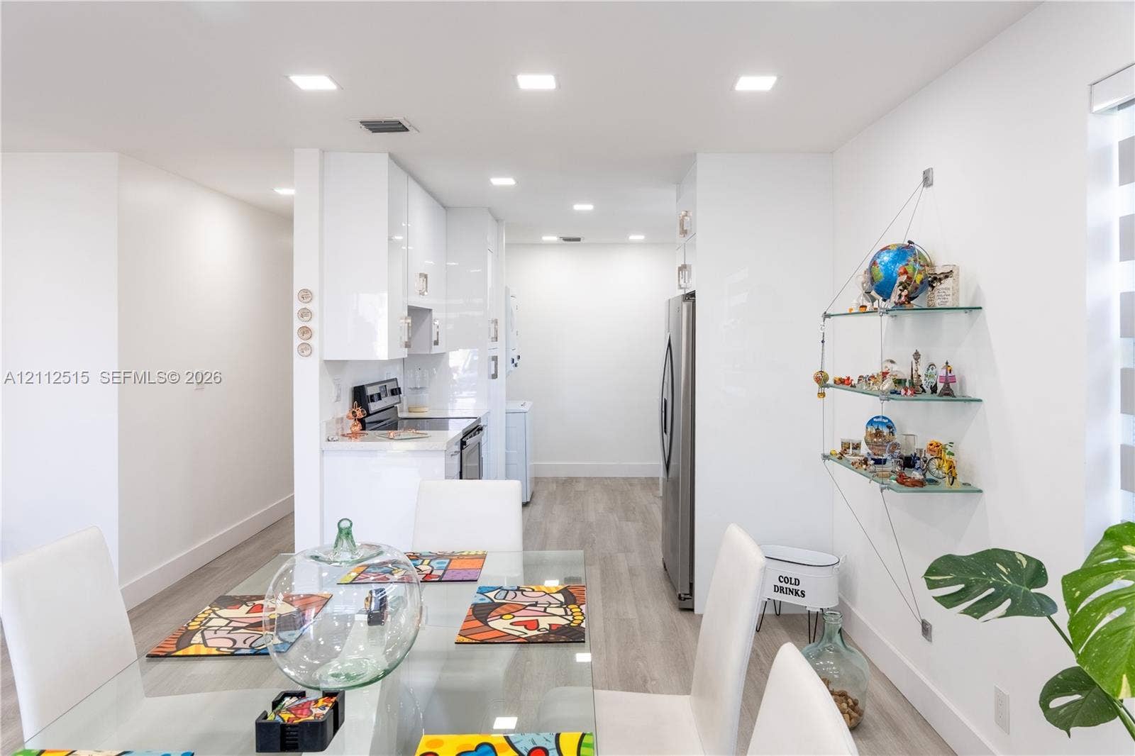 Hallandale Beach, FL 33009 Glossy white flat-panel cabinetry, stainless steel appliances, wood-finish flooring, and recessed ceiling lighting