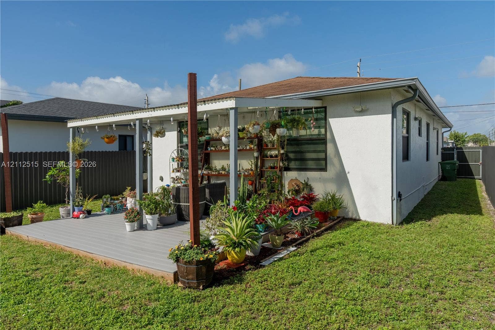 Hallandale Beach, FL 33009 Exterior featuring a covered patio with composite decking, corrugated roofing, and privacy fencing
