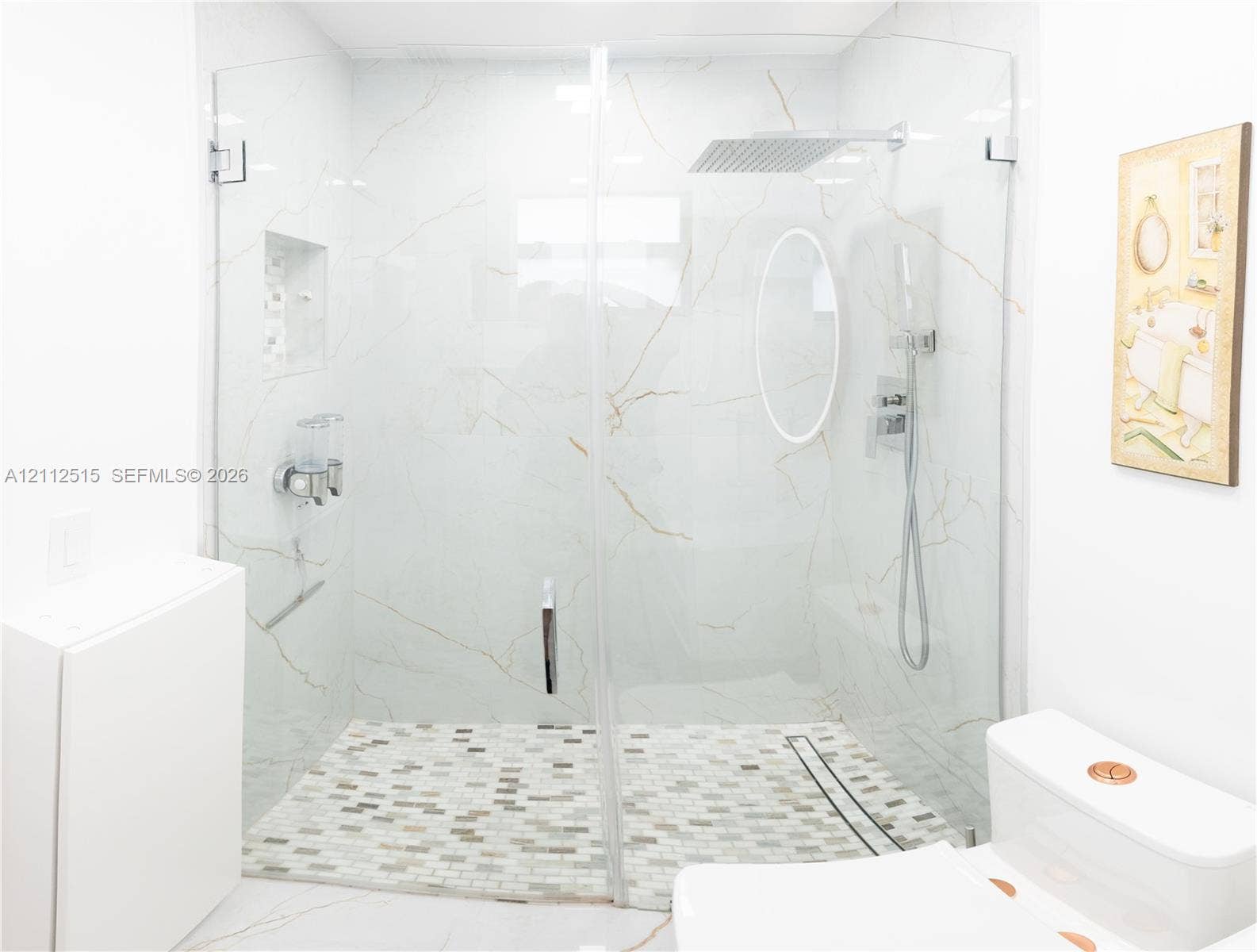 Hallandale Beach, FL 33009 Walk-in shower featuring large-format wall tile with gold veining, a frameless glass enclosure, a mosaic-tiled floor, a rainfall showerhead, and a built-in recessed wall niche