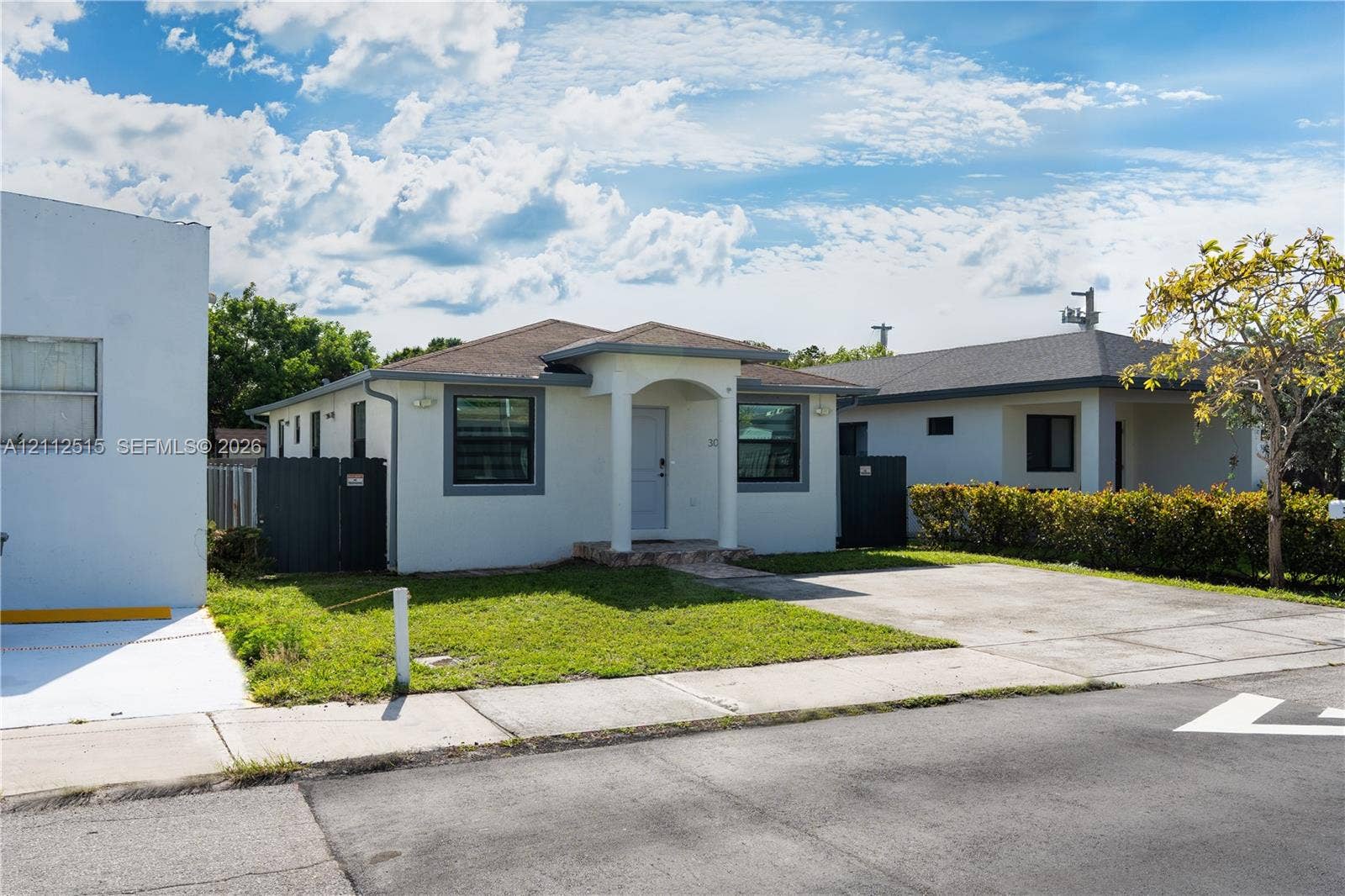 Hallandale Beach, FL 33009 Single-story exterior featuring a hip roof, covered front entryway, concrete driveway, and solid-surface privacy fencing