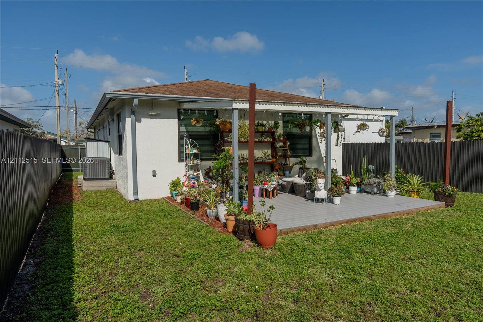 Hallandale Beach, FL 33009 Fenced backyard featuring a painted deck, covered patio structure, and exterior stucco finish
