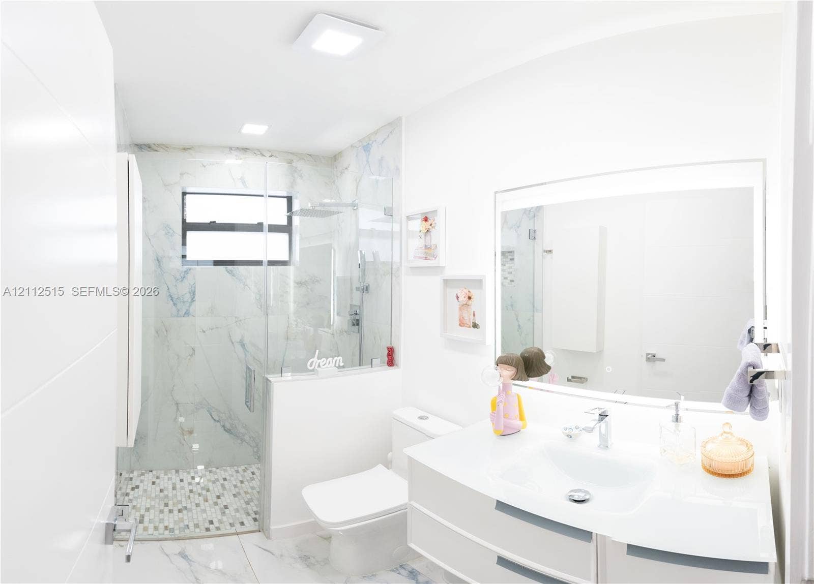 Hallandale Beach, FL 33009 Floating vanity with integrated sink, walk-in shower featuring glass enclosure, stone-finish wall tiling, mosaic tile shower floor, and large-format floor tile
