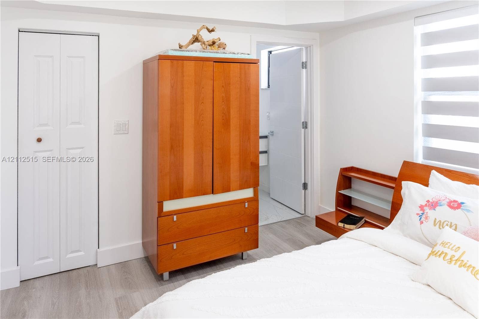 Hallandale Beach, FL 33009 Room featuring wood-finish flooring, a white bifold closet door, and a horizontal-slat window shade