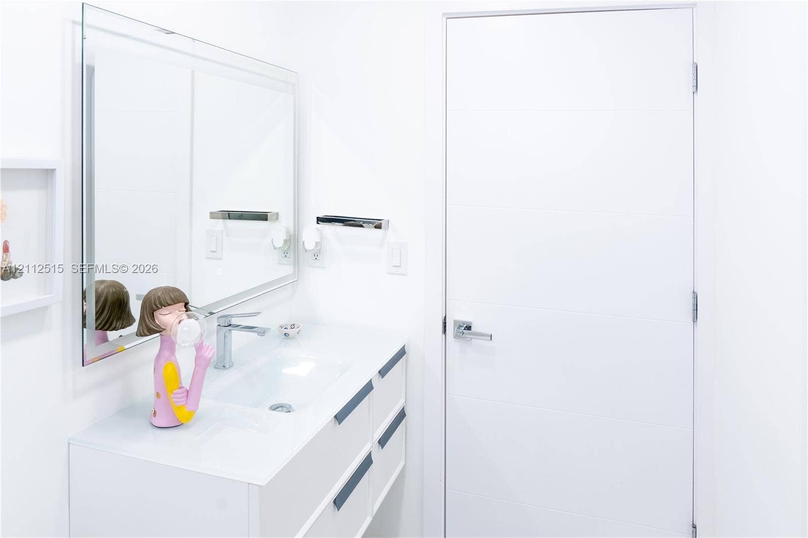 Hallandale Beach, FL 33009 Wall-mounted mirror, white floating vanity with integrated sink, chrome faucet, and flat-panel door with metallic lever hardware