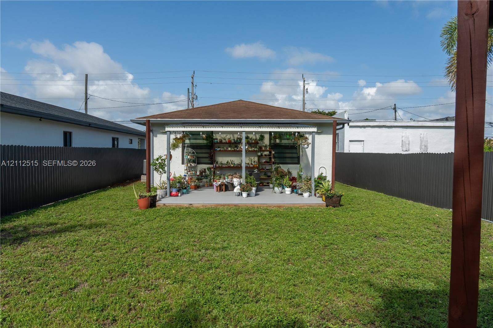 Hallandale Beach, FL 33009 Backyard featuring a covered patio, a level lawn, and perimeter metal fencing