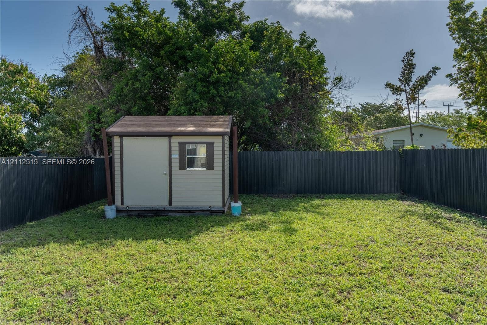 Hallandale Beach, FL 33009 Backyard area featuring a storage shed, grass lawn, and dark metal privacy fencing