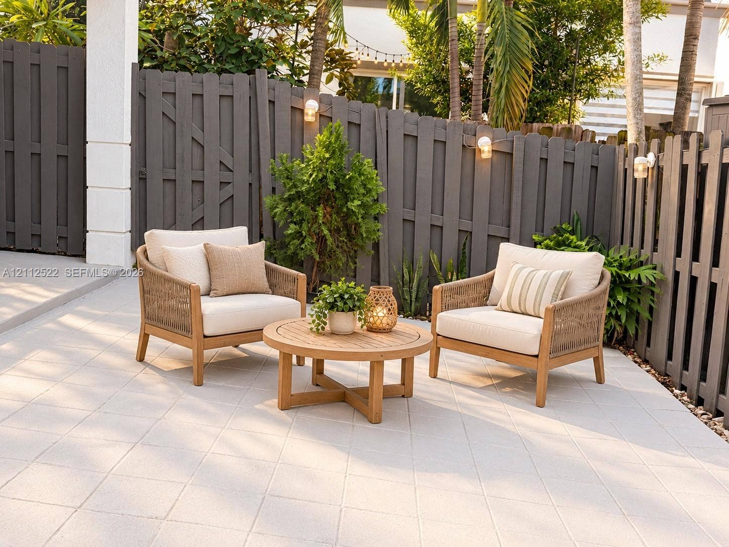7822 NW 116th Avenue, Doral, FL 33178 Tiled patio featuring a privacy fence, mature landscaping, and wall-mounted exterior lighting