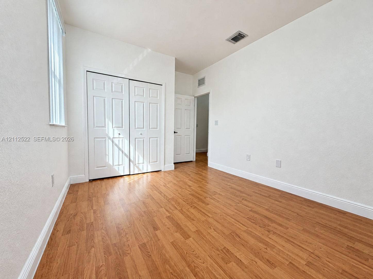 7822 NW 116th Avenue, Doral, FL 33178 Wood-finish flooring, double-door closet, and vertical window blinds