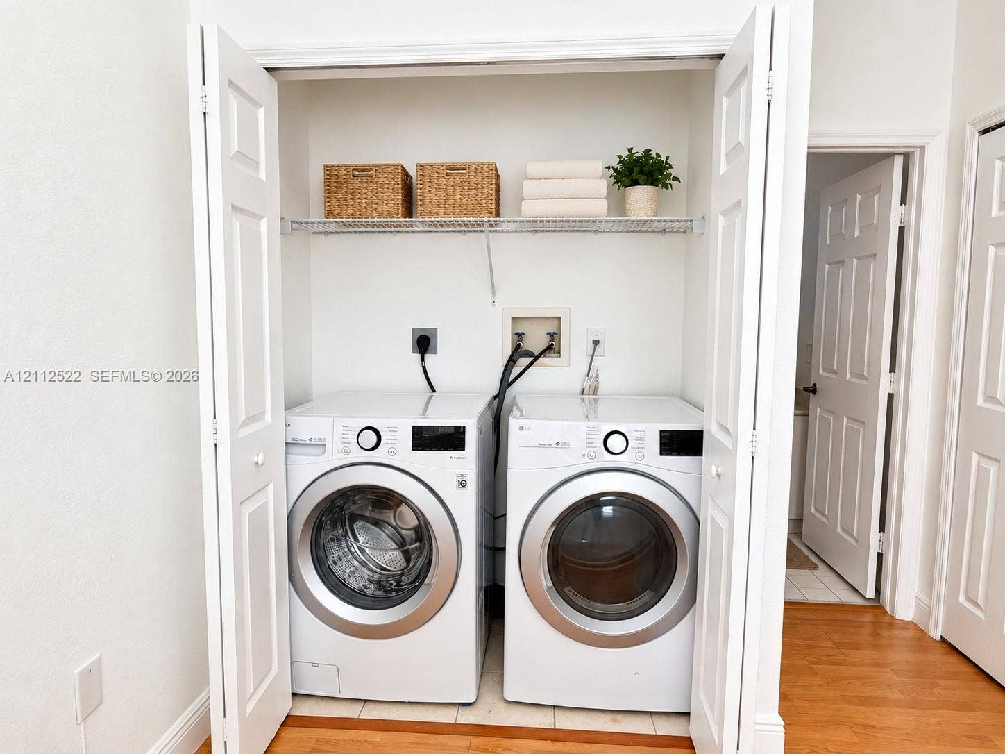 7822 NW 116th Avenue, Doral, FL 33178 Laundry closet featuring dual white bi-fold doors, white interior walls, and an overhead wire shelving unit