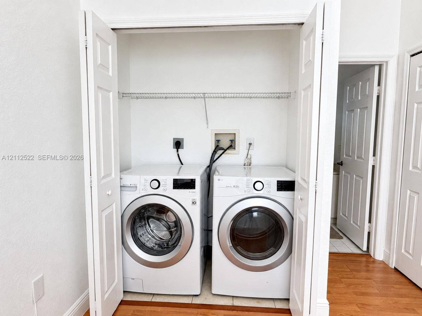 7822 NW 116th Avenue, Doral, FL 33178 Laundry closet featuring white bi-fold doors, white interior walls, and an overhead wire shelving unit