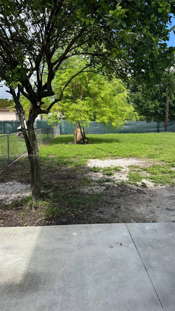 351 E 14th Street, #353, Hialeah, Hialeah, FL 33010 Concrete patio area with an expansive outdoor space featuring mature trees and chain-link perimeter fencing