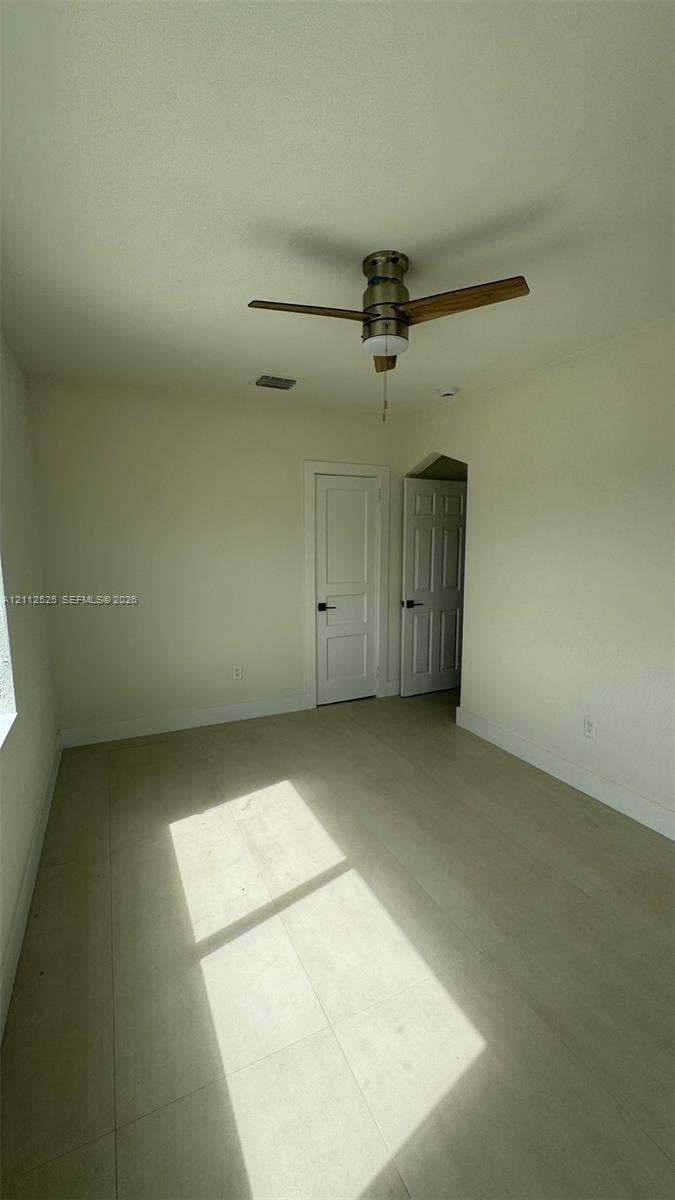 351 E 14th Street, #353, Hialeah, Hialeah, FL 33010 Interior room featuring light-toned flooring, a brushed metal ceiling fan, and two interior doors with panel detailing