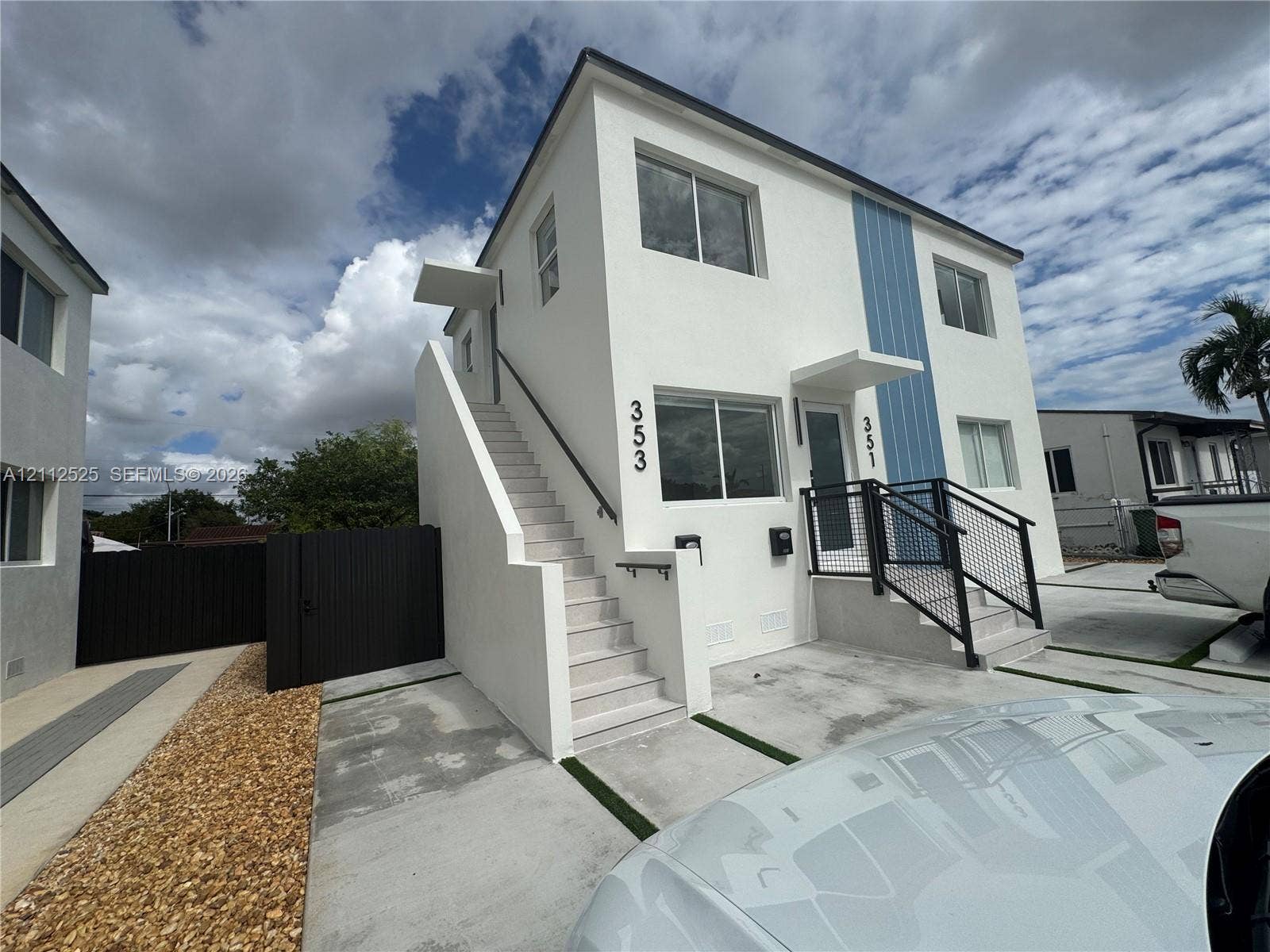 351 E 14th Street, #353, Hialeah, Hialeah, FL 33010 Two-story exterior featuring white stucco finish, blue vertical siding accents, concrete staircases with metal handrails, and a dedicated concrete parking area
