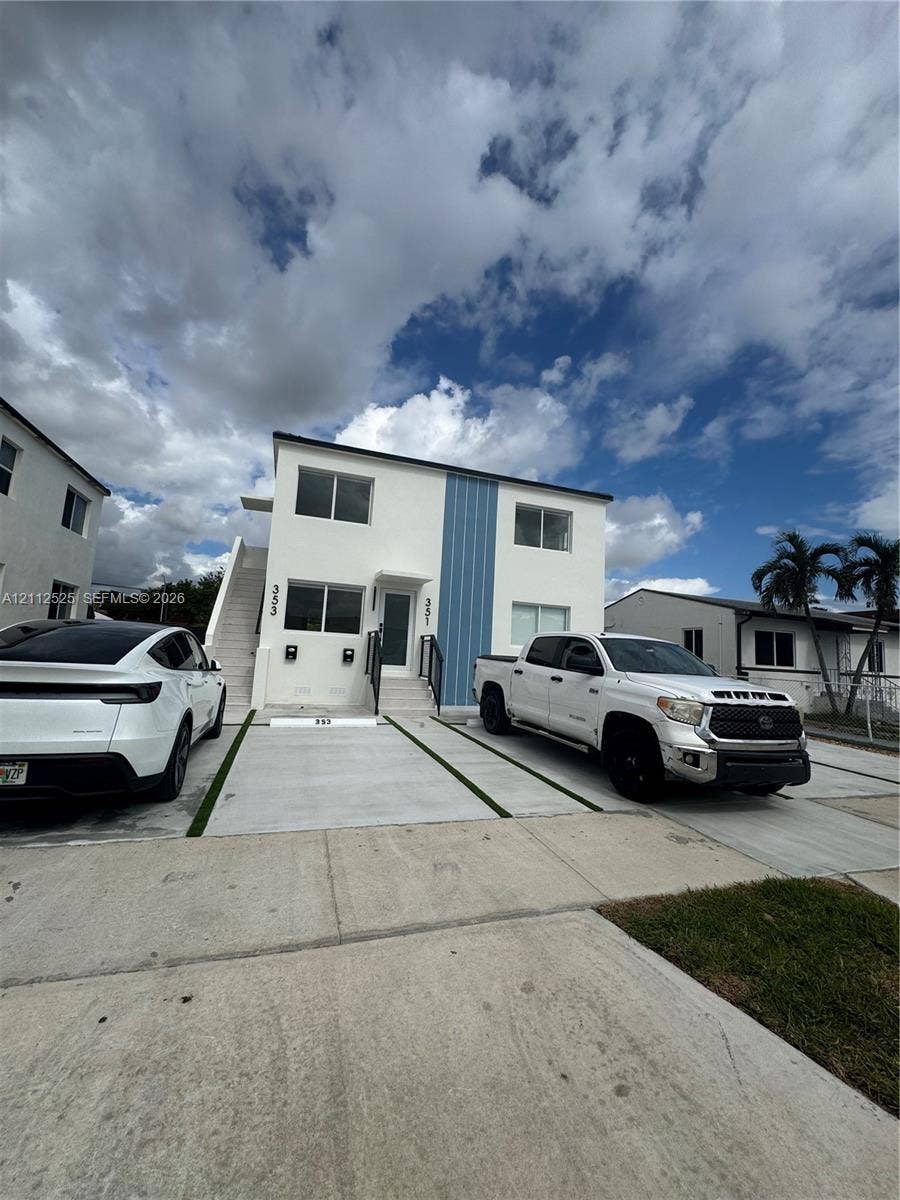 351 E 14th Street, #353, Hialeah, Hialeah, FL 33010 Two-story structure featuring a smooth white stucco exterior with vertical blue panel accents and designated concrete parking pads