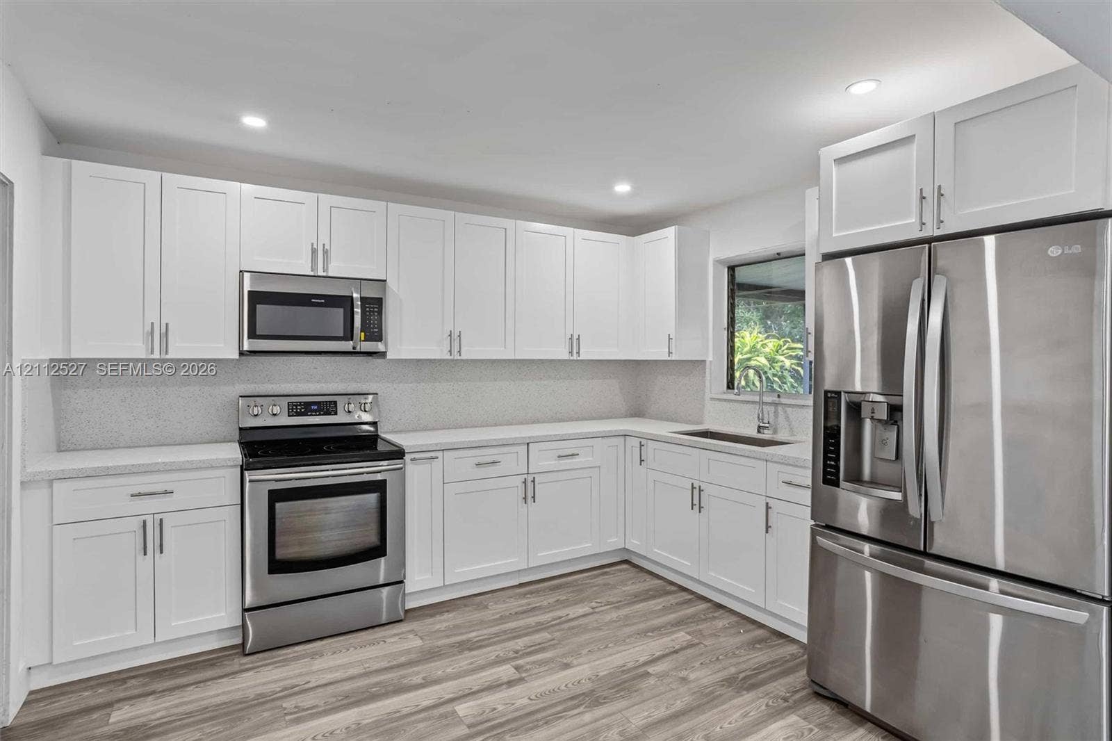2517 Polk Street, Hollywood, Hollywood, FL 33020 Kitchen featuring white Shaker-style cabinetry, stainless steel appliances, speckled stone-finish countertops, tile backsplash, and wood-finish flooring