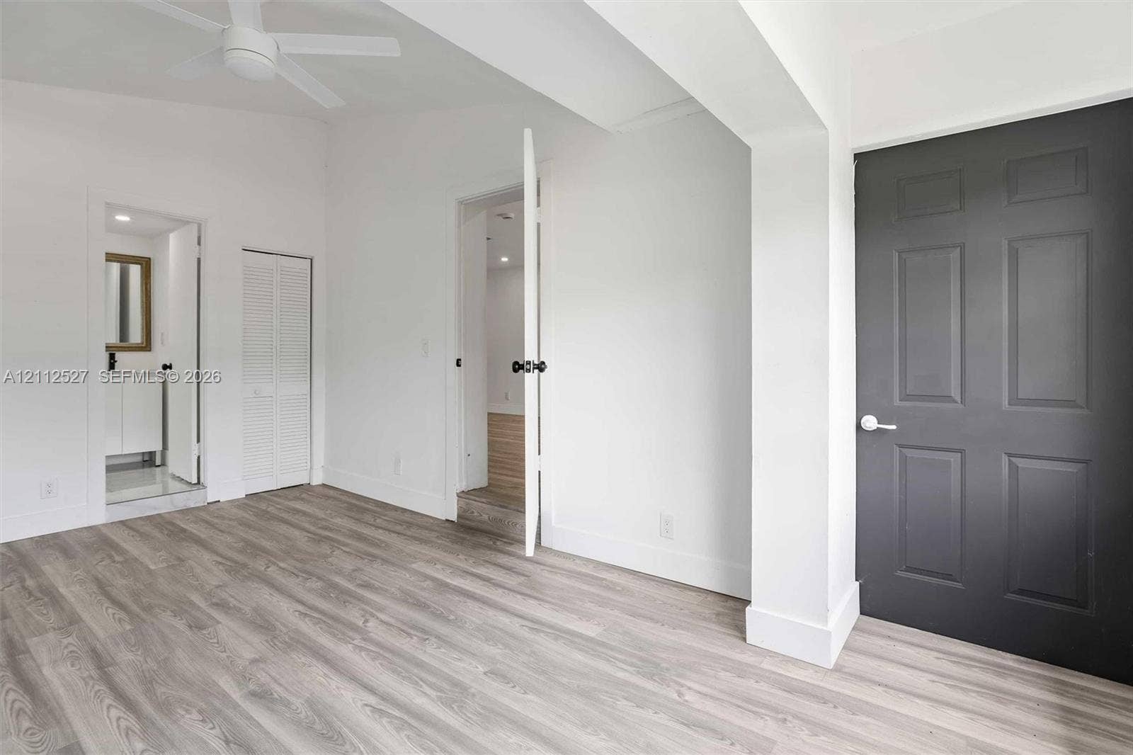 2517 Polk Street, Hollywood, Hollywood, FL 33020 Interior space featuring wood-finish flooring, vaulted ceilings with a mounted ceiling fan, a charcoal-toned paneled door, and white louvered closet doors