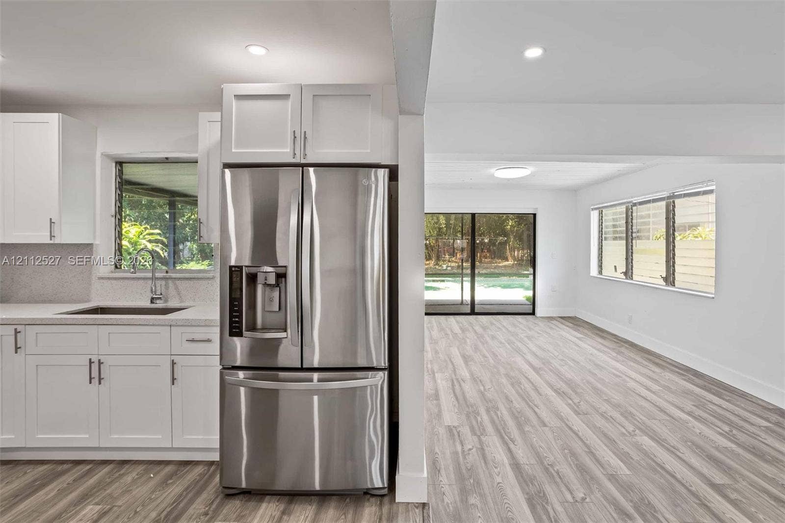 2517 Polk Street, Hollywood, Hollywood, FL 33020 Kitchen featuring white shaker-style cabinetry, quartz countertops, stainless steel refrigerator, and wood-finish flooring with sliding glass doors
