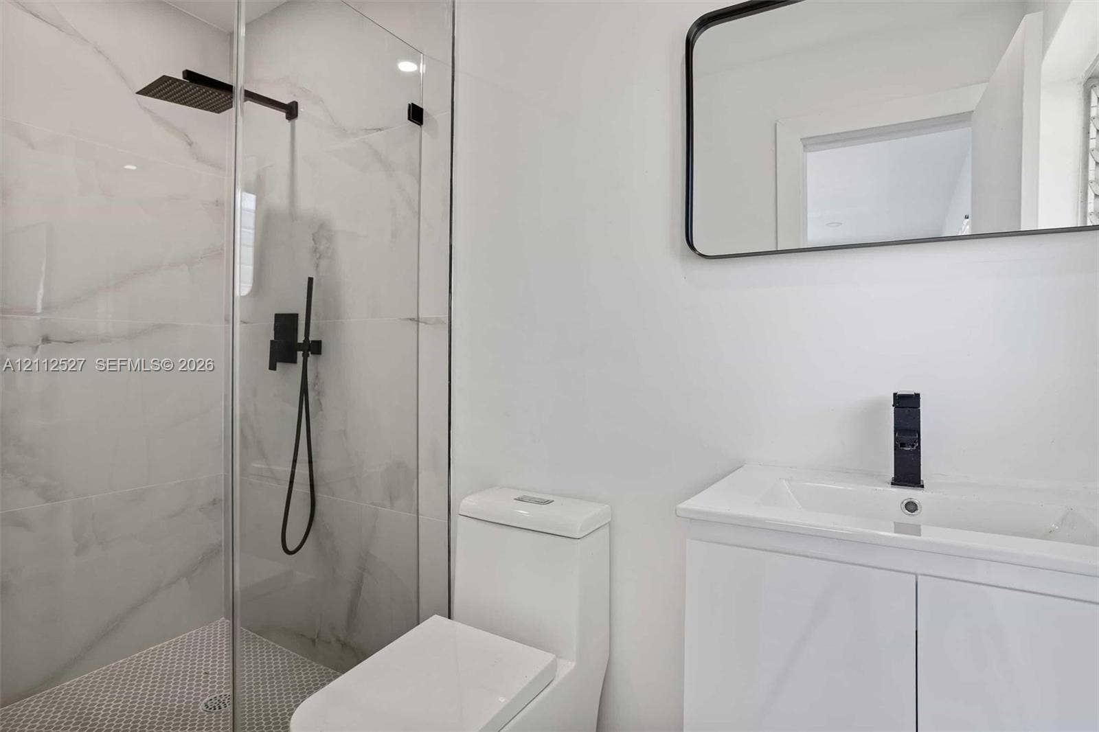 2517 Polk Street, Hollywood, Hollywood, FL 33020 Walk-in shower featuring floor-to-ceiling stone-finish tile, matte black rainfall shower head, glass enclosure, white vanity with integrated sink, and matte black faucet