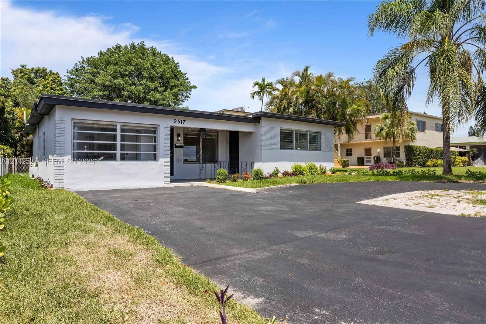 2517 Polk Street, Hollywood, Hollywood, FL 33020 Single-story residence featuring a painted masonry exterior, a recessed covered entryway, multi-pane horizontal windows, and an asphalt driveway