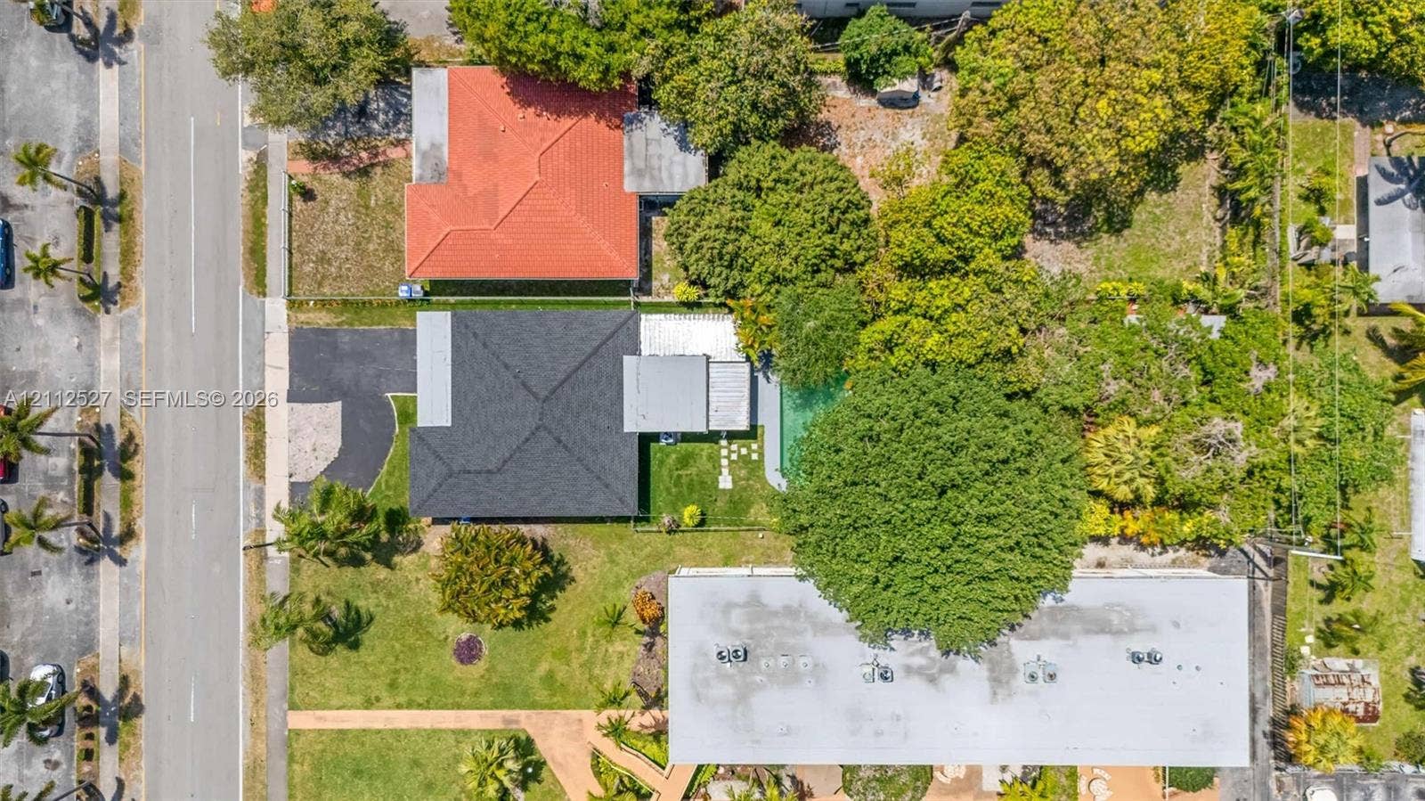 2517 Polk Street, Hollywood, Hollywood, FL 33020 Aerial view of property featuring a dark-shingle roof, paved driveway, swimming pool, manicured lawn, and mature canopy trees
