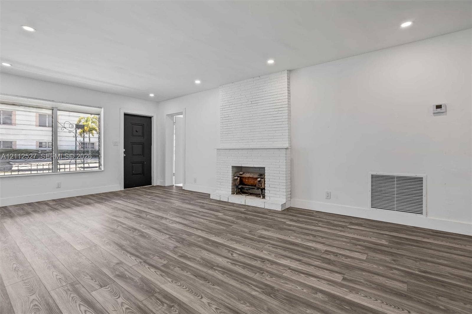 2517 Polk Street, Hollywood, Hollywood, FL 33020 Living area featuring wood-finish flooring, a white painted brick fireplace, recessed lighting, and a black exterior door