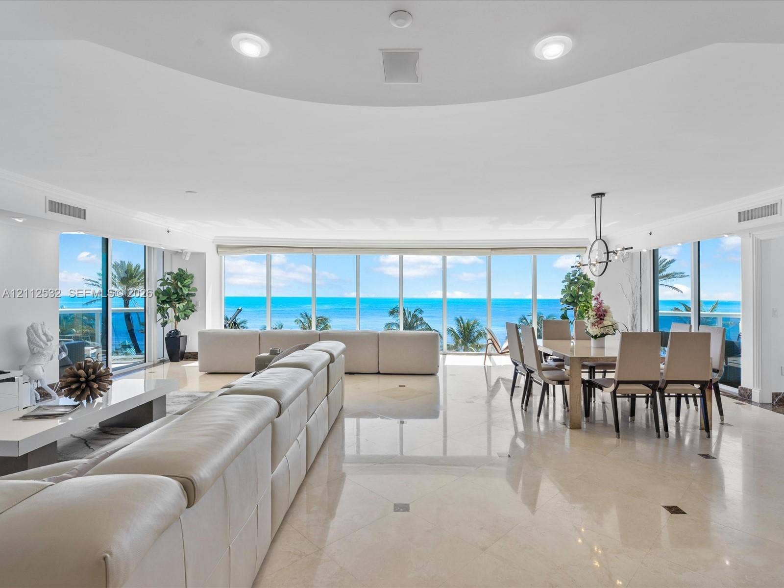 18911 Collins Avenue, #601, Sunny Isles Beach, FL 33160 Open-concept living space featuring floor-to-ceiling windows, polished stone flooring, recessed lighting, and expansive water scenery