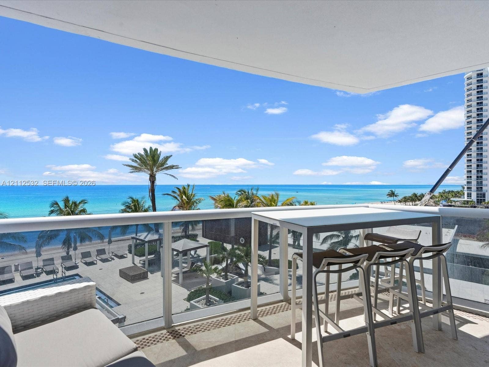 18911 Collins Avenue, #601, Sunny Isles Beach, FL 33160 Covered balcony featuring glass railing, stone flooring, and expansive ocean scenery