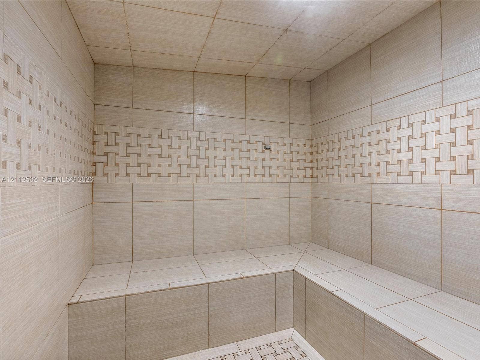 18911 Collins Avenue, #601, Sunny Isles Beach, FL 33160 Tiled steam shower featuring built-in bench seating, large-format wall tiles, and decorative basket-weave accent detailing