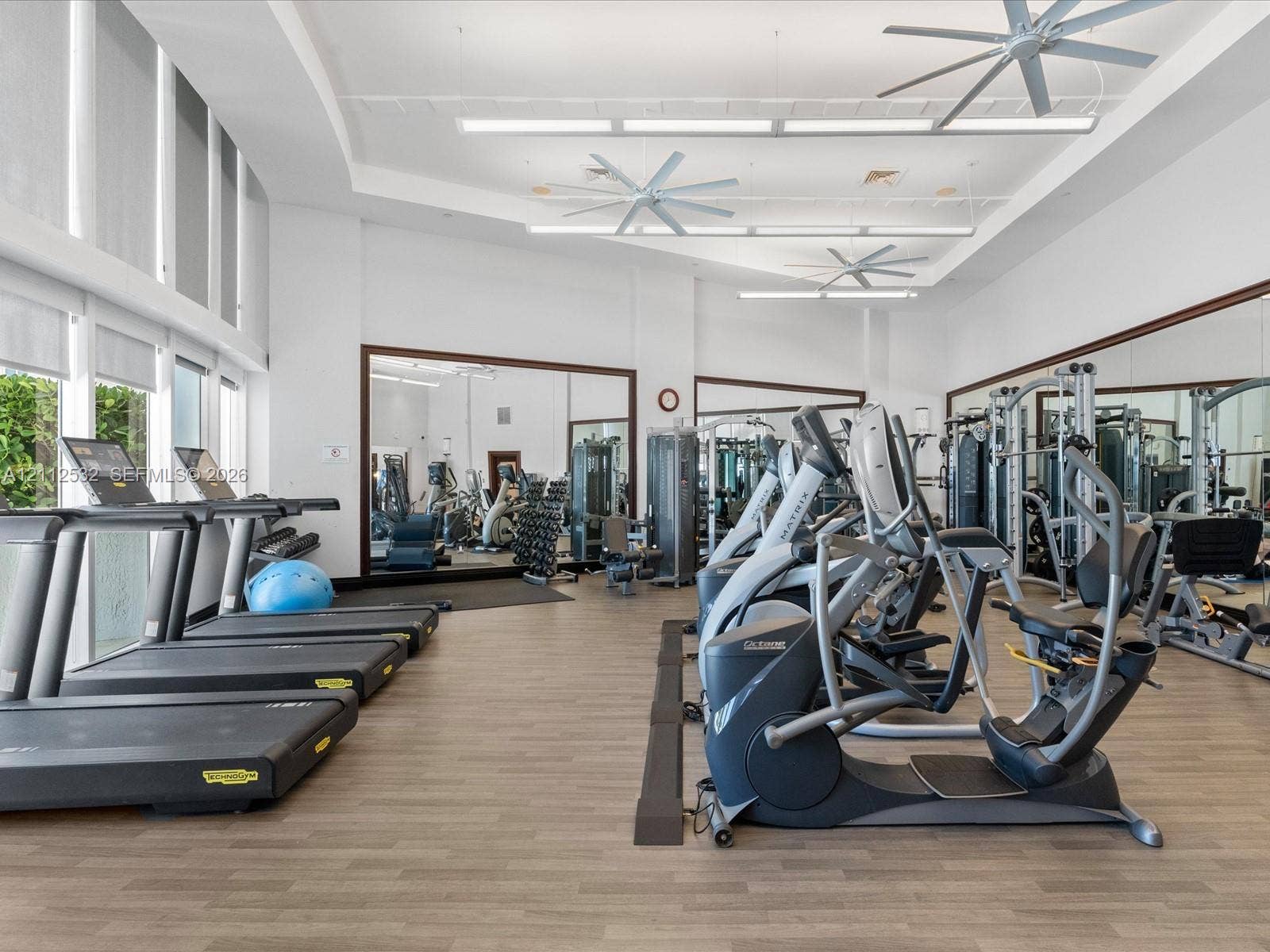 18911 Collins Avenue, #601, Sunny Isles Beach, FL 33160 Fitness center featuring wood-finish flooring, floor-to-ceiling mirrored walls, recessed linear lighting, and ceiling-mounted fans