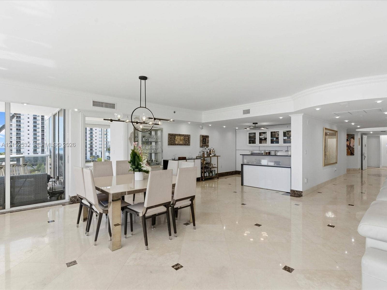 18911 Collins Avenue, #601, Sunny Isles Beach, FL 33160 Open-concept area featuring polished stone flooring with decorative inlays, a built-in wet bar with cabinetry, recessed lighting, a modern multi-arm chandelier, and floor-to-ceiling glass sliding doors