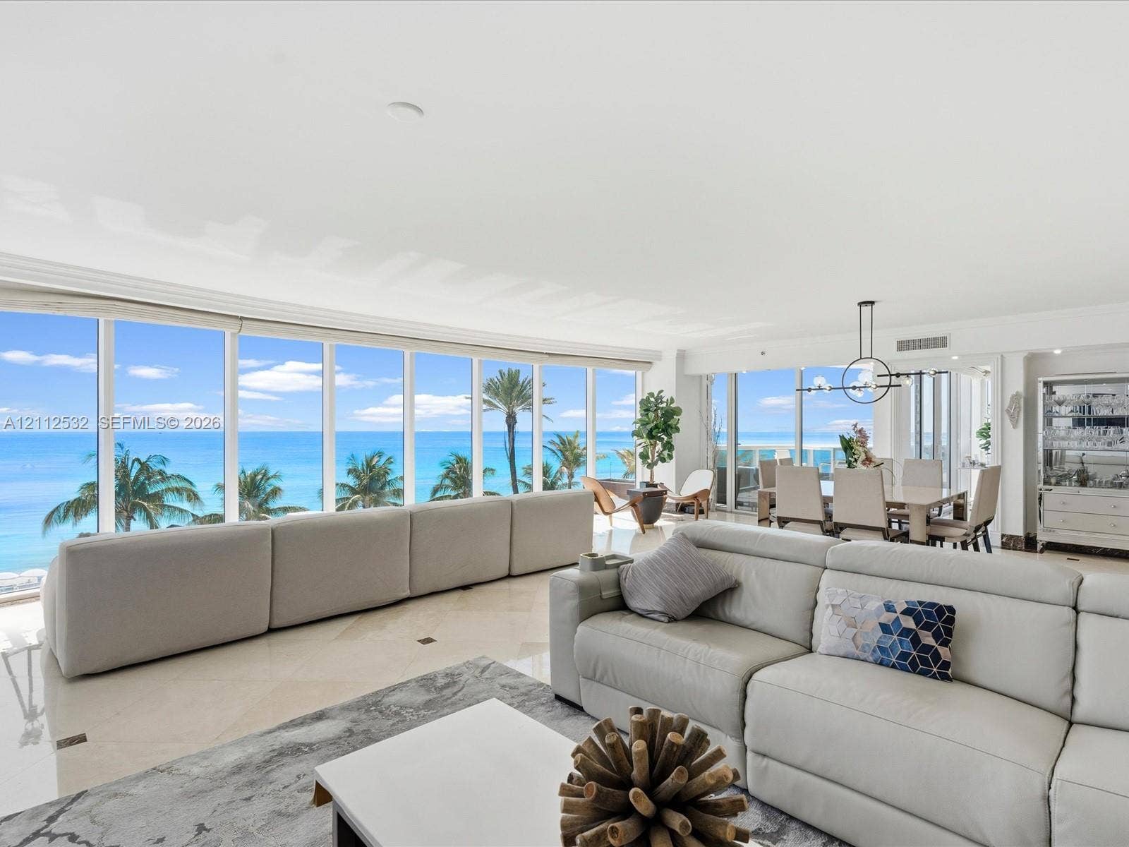 18911 Collins Avenue, #601, Sunny Isles Beach, FL 33160 Open-concept living space featuring floor-to-ceiling glass windows, polished stone flooring, and expansive ocean and coastal scenery