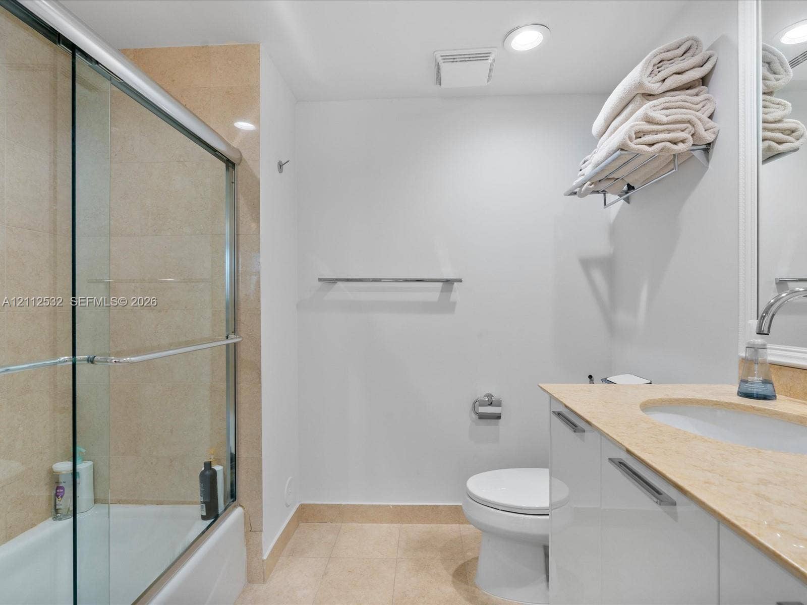 18911 Collins Avenue, #601, Sunny Isles Beach, FL 33160 Bathroom featuring a glass-enclosed shower with tiled surround, stone countertop, white vanity cabinetry with chrome hardware, and recessed lighting