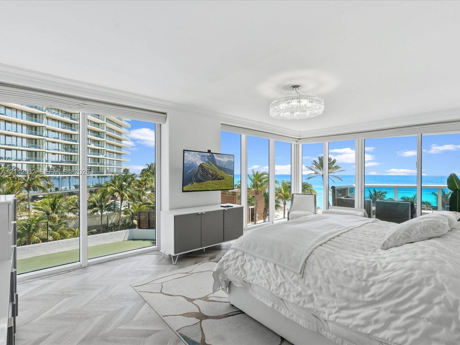 18911 Collins Avenue, #601, Sunny Isles Beach, FL 33160 Floor-to-ceiling windows, herringbone-patterned wood-finish flooring, recessed crown molding, and a crystal-accented drum chandelier