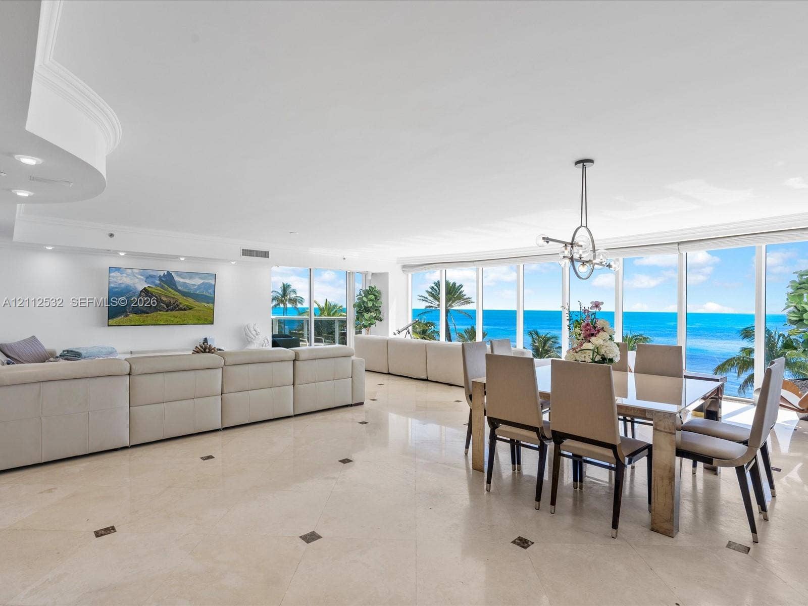 18911 Collins Avenue, #601, Sunny Isles Beach, FL 33160 Open-concept floor plan featuring expansive floor-to-ceiling windows, polished stone tile flooring with decorative inlay, recessed lighting, and a modern tiered ceiling detail