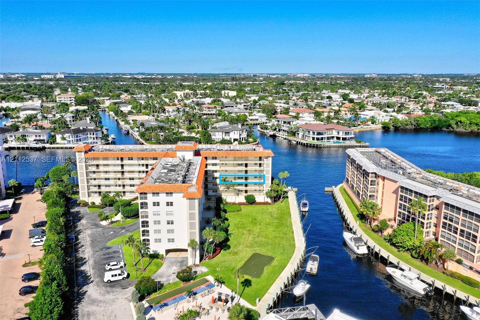 2871 N Ocean Boulevard, #R360, Boca Raton, FL 33431 Multi-story residential building with terracotta-tiled roof, featuring water-front positioning, direct canal access, an on-site putting green, and manicured landscaping