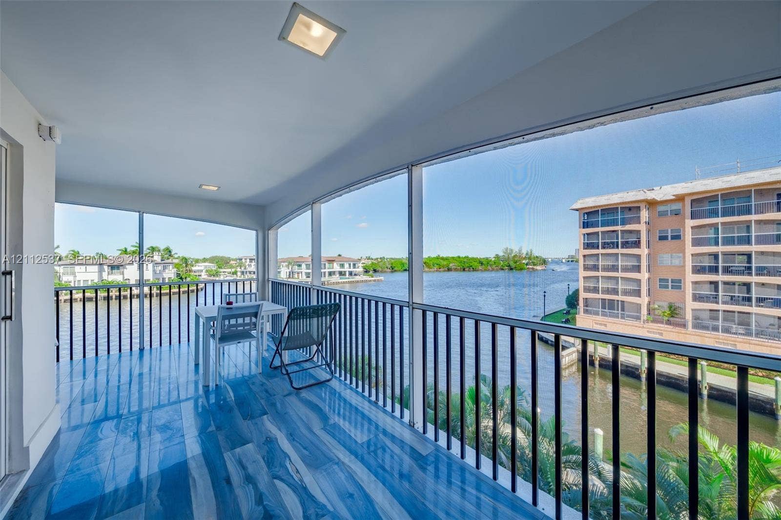 2871 N Ocean Boulevard, #R360, Boca Raton, FL 33431 Screened balcony featuring wood-finish flooring, recessed lighting, and black metal railings overlooking the waterway