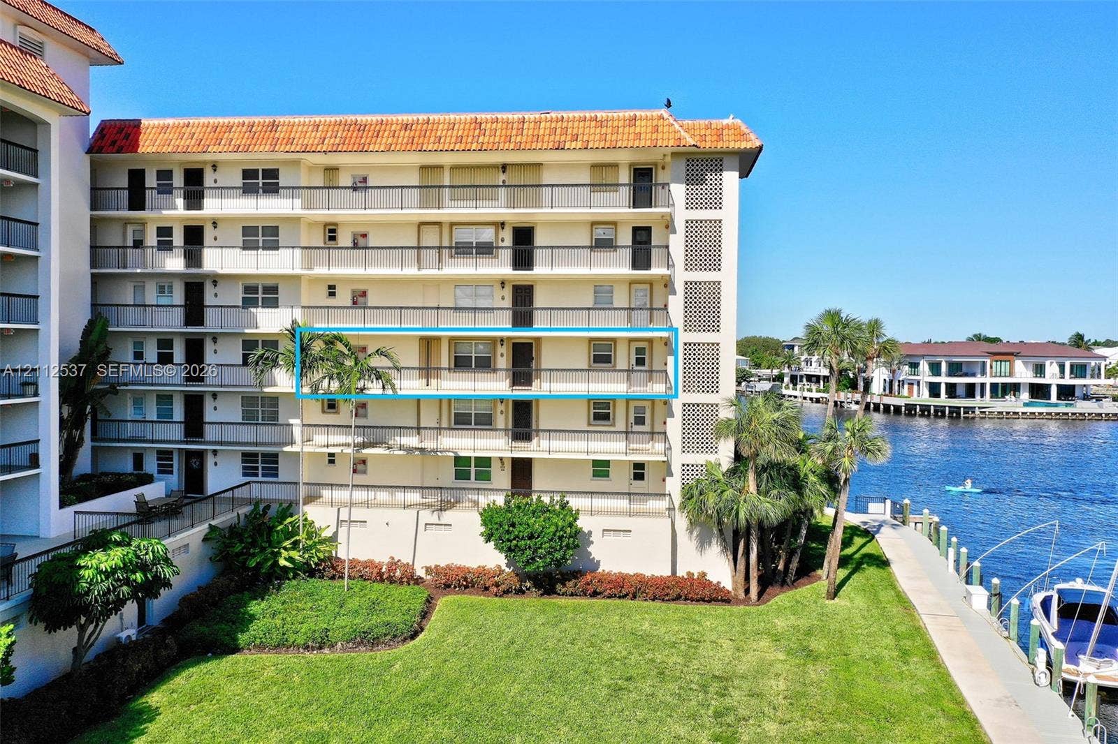 2871 N Ocean Boulevard, #R360, Boca Raton, FL 33431 Multi-story waterfront residential building featuring a terracotta tile roof, wrap-around balconies with metal railings, and direct access to a private dock