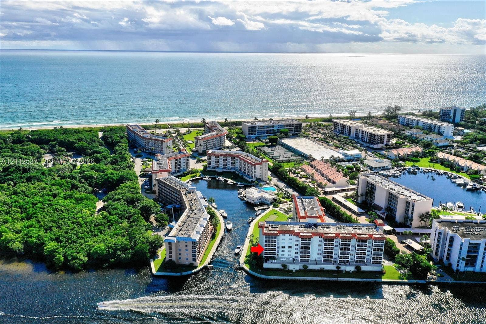 2871 N Ocean Boulevard, #R360, Boca Raton, FL 33431 Aerial perspective featuring a waterfront multi-story building positioned along a canal with direct ocean access, surrounded by dense coastal vegetation and maintained grounds
