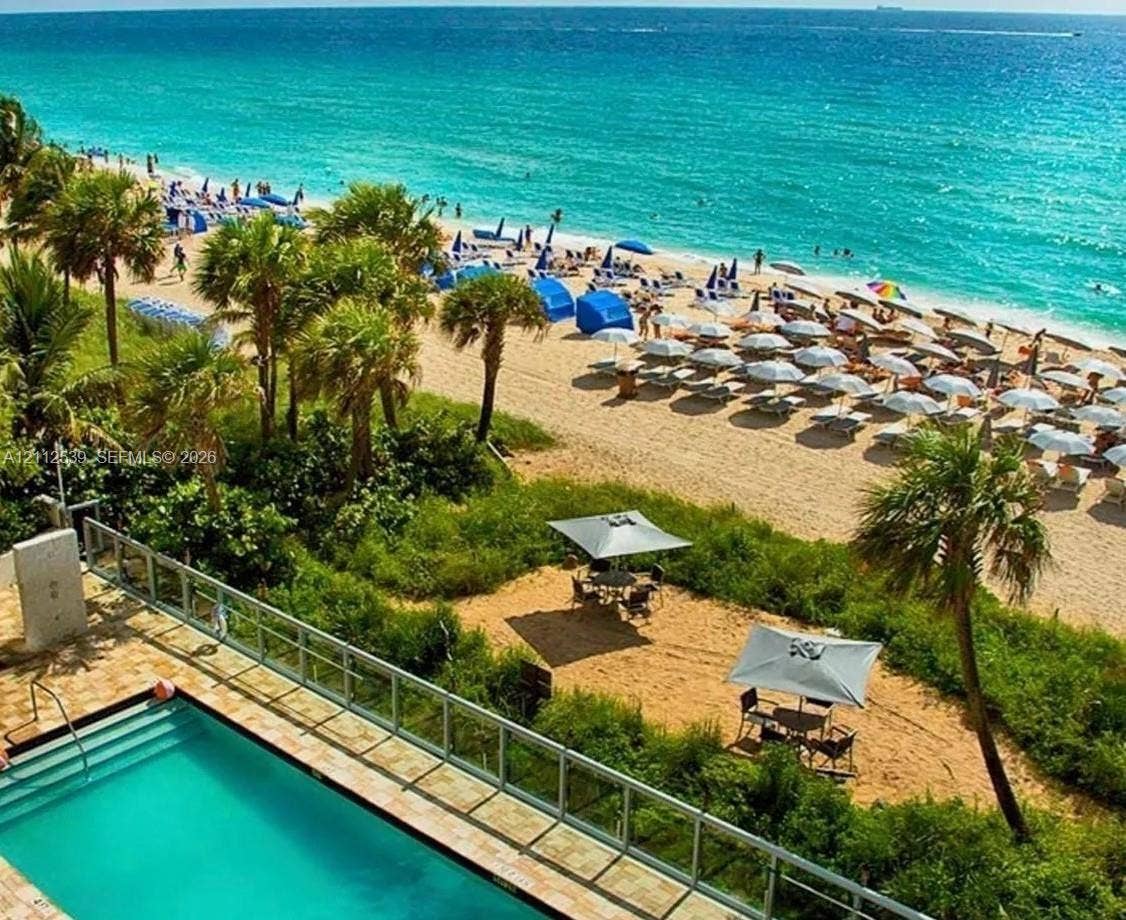17315 Collins Avenue, #705, Sunny Isles Beach, FL 33160 Swimming pool with stone-finish decking, glass panel railing, and direct proximity to sand dunes and the coastline