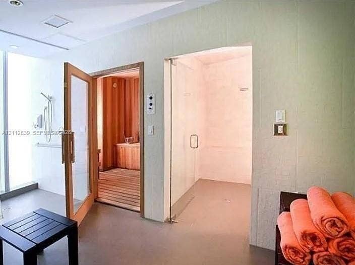 17315 Collins Avenue, #705, Sunny Isles Beach, FL 33160 Sauna featuring cedar paneling and wood-slat flooring, accompanied by a glass-enclosed steam shower with tile surround and wall-mounted shower hardware
